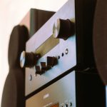 A detailed view of a sleek black audio stereo system highlighting control knobs.
